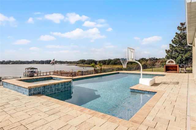 view of pool featuring an in ground hot tub, a patio, and a water view