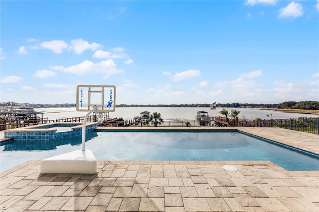 view of swimming pool featuring an in ground hot tub, a water view, and a patio