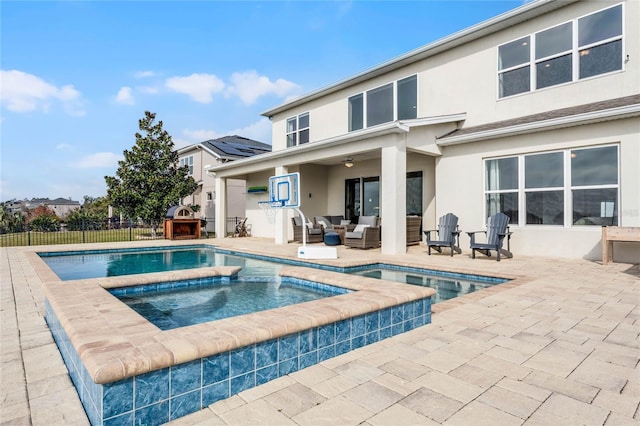 rear view of house featuring a swimming pool with hot tub, a patio, and an outdoor living space with a fireplace