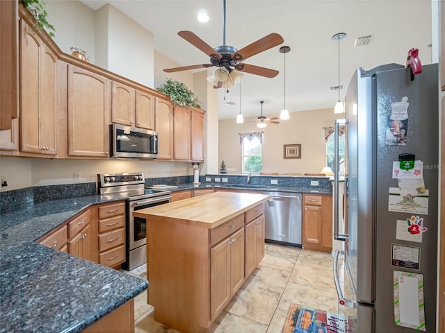 kitchen with wood counters, kitchen peninsula, ceiling fan, stainless steel appliances, and a kitchen island