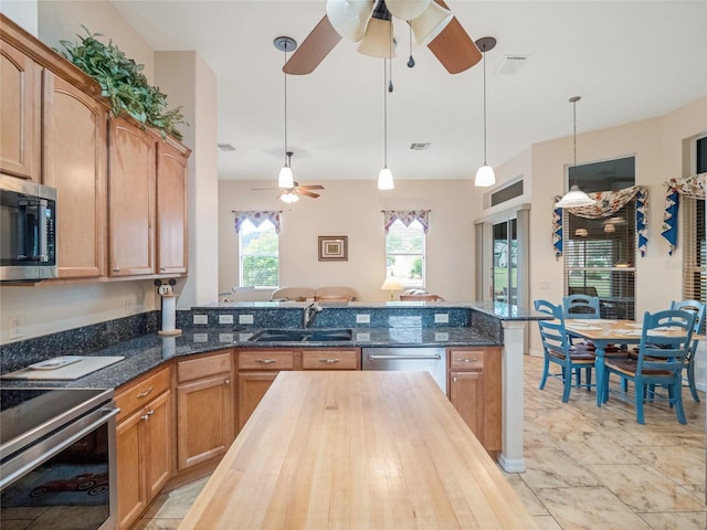 kitchen featuring ceiling fan, wooden counters, sink, hanging light fixtures, and appliances with stainless steel finishes