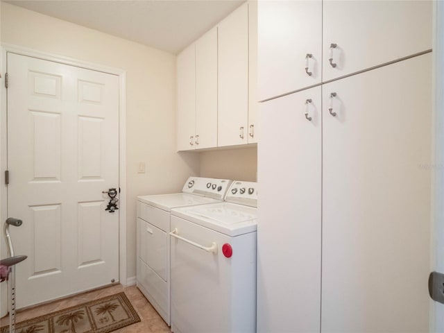 clothes washing area featuring cabinets, light tile patterned floors, and washing machine and clothes dryer