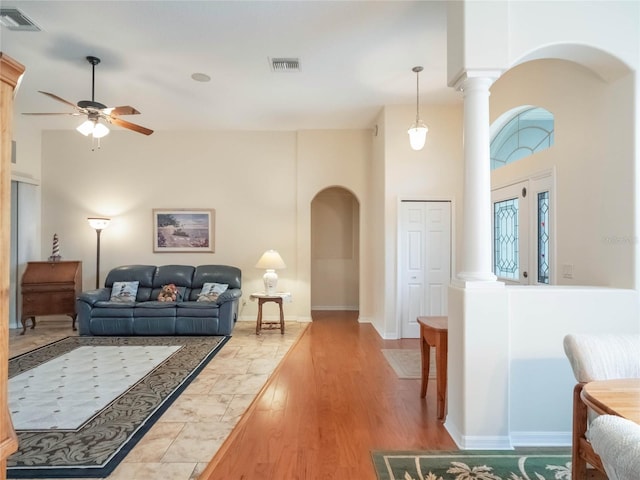 living room with ceiling fan, wood-type flooring, and a towering ceiling