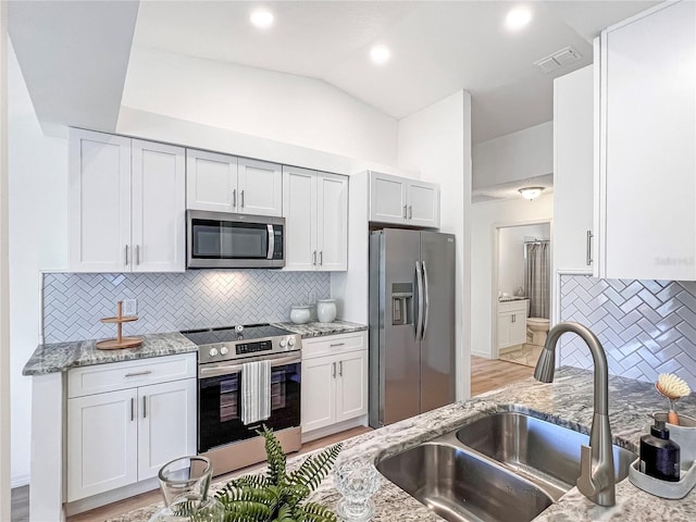 kitchen featuring stainless steel appliances, white cabinets, tasteful backsplash, and sink