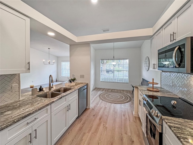 kitchen with white cabinets, decorative light fixtures, stainless steel appliances, decorative backsplash, and sink