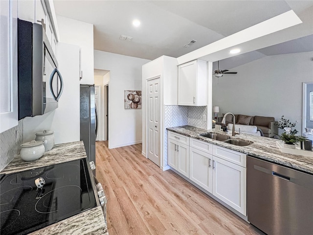 kitchen with decorative backsplash, sink, white cabinetry, appliances with stainless steel finishes, and light stone counters