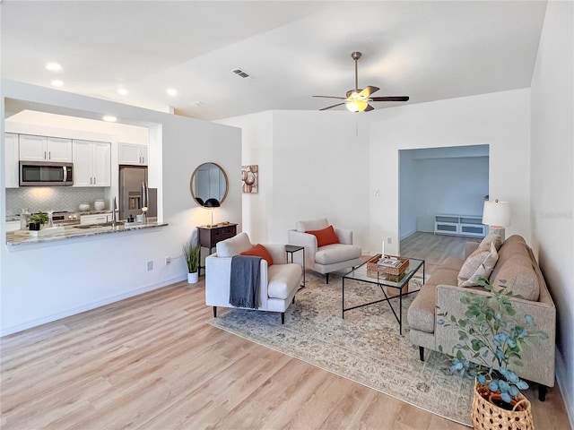 living room featuring ceiling fan, sink, and light hardwood / wood-style flooring