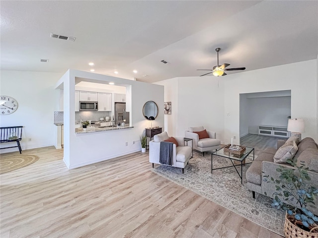 living room featuring ceiling fan, light wood-type flooring, and lofted ceiling