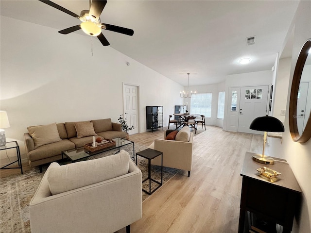 living room with light wood-type flooring, lofted ceiling, and ceiling fan with notable chandelier