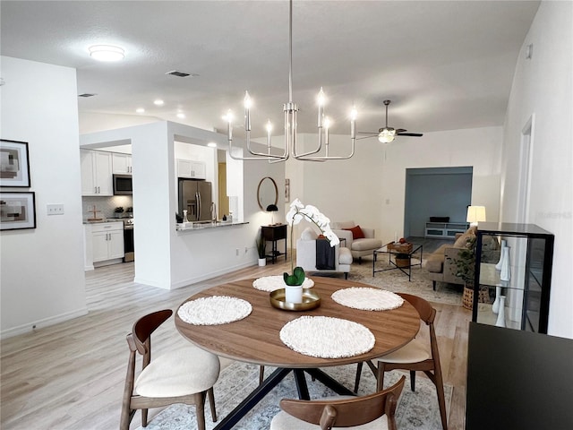 dining room featuring ceiling fan with notable chandelier and light hardwood / wood-style floors