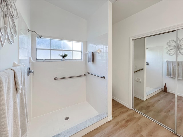 bathroom with hardwood / wood-style floors and tiled shower