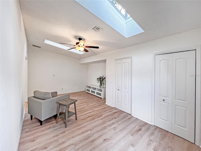 living area with a textured ceiling, ceiling fan, lofted ceiling, and light hardwood / wood-style floors