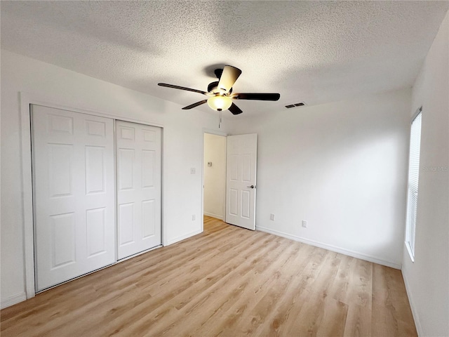 unfurnished bedroom featuring ceiling fan, light hardwood / wood-style floors, a textured ceiling, and a closet