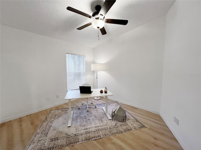 unfurnished office featuring ceiling fan, a textured ceiling, and light wood-type flooring