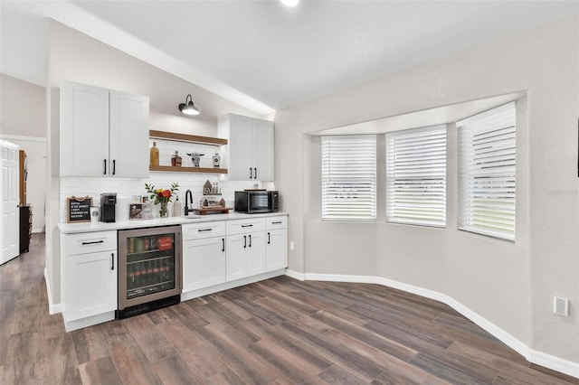 bar with decorative backsplash, white cabinets, beverage cooler, and vaulted ceiling