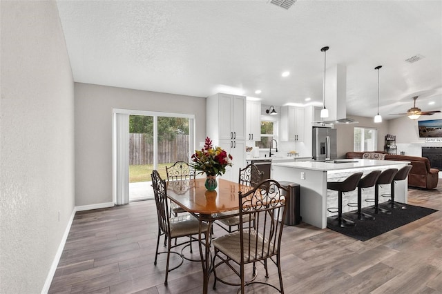 dining area featuring ceiling fan, dark hardwood / wood-style flooring, sink, and a textured ceiling