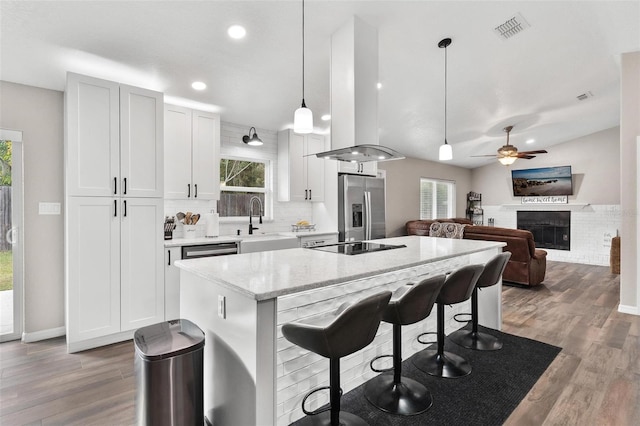 kitchen with decorative light fixtures, a fireplace, sink, stainless steel appliances, and island range hood