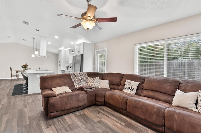 living room with vaulted ceiling, ceiling fan, and wood-type flooring