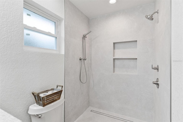 bathroom featuring toilet and a tile shower