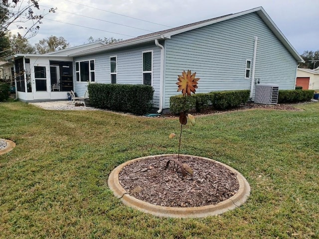 rear view of property featuring central AC unit, a yard, and a sunroom