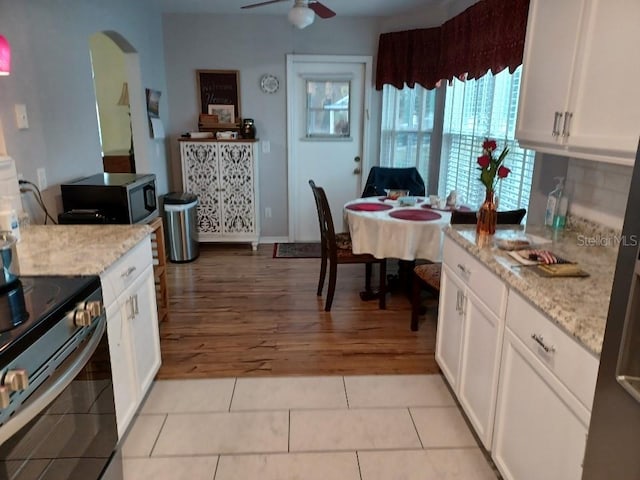 kitchen featuring white cabinetry, light stone countertops, light tile patterned flooring, and appliances with stainless steel finishes