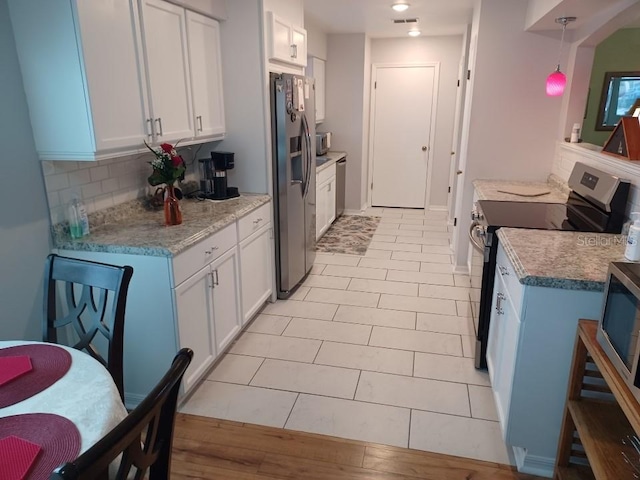 kitchen featuring light tile patterned floors, pendant lighting, stainless steel appliances, decorative backsplash, and white cabinets