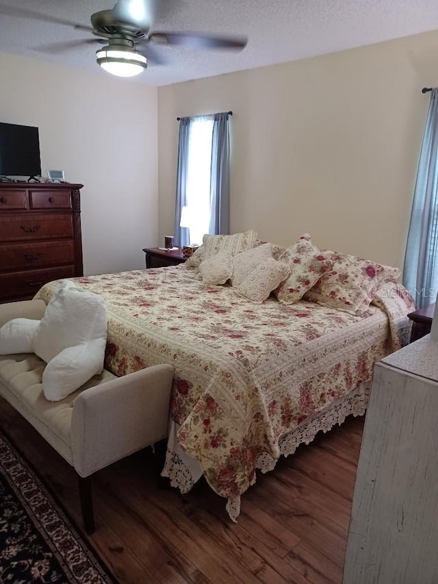 bedroom featuring ceiling fan, dark hardwood / wood-style flooring, and a textured ceiling