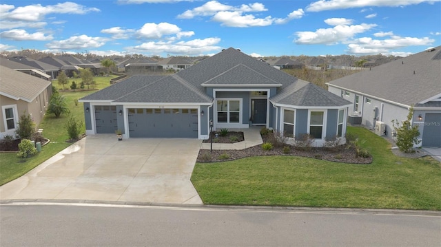 view of front of home with a front yard, a shingled roof, concrete driveway, a garage, and a residential view