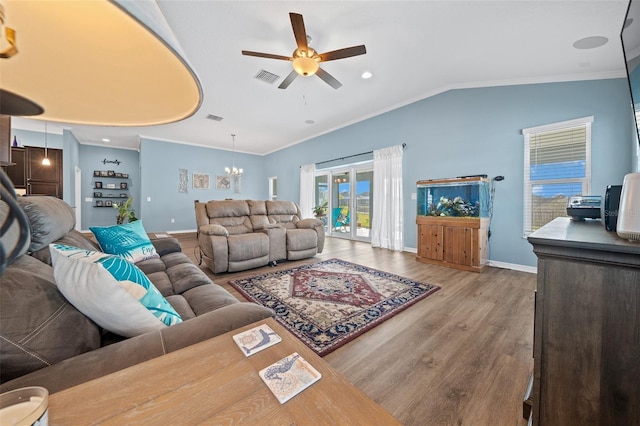 living room with visible vents, ornamental molding, ceiling fan with notable chandelier, wood finished floors, and vaulted ceiling