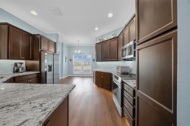 kitchen with visible vents, wood finished floors, dark brown cabinetry, appliances with stainless steel finishes, and light stone countertops