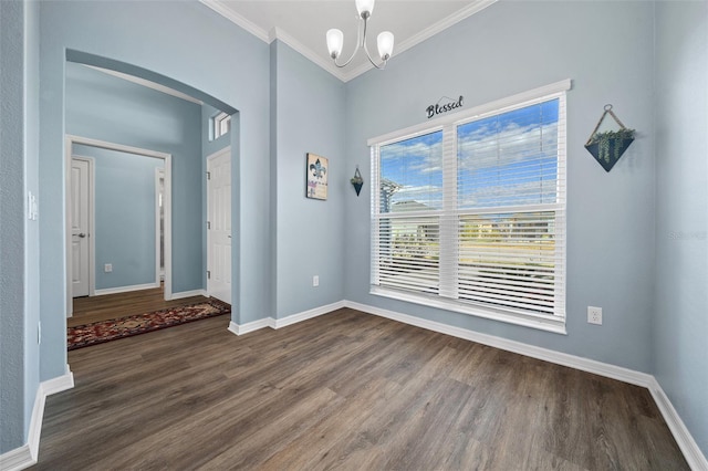 entrance foyer with a notable chandelier, ornamental molding, dark wood finished floors, arched walkways, and baseboards