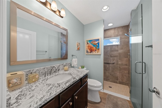 bathroom with vanity, wood finished floors, recessed lighting, a stall shower, and toilet