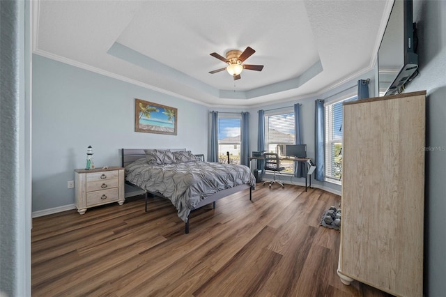 bedroom featuring a tray ceiling, baseboards, wood finished floors, and ornamental molding