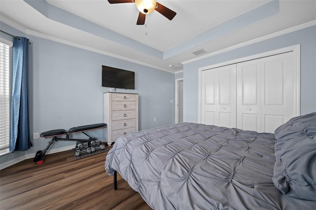 bedroom featuring visible vents, crown molding, a raised ceiling, and wood finished floors