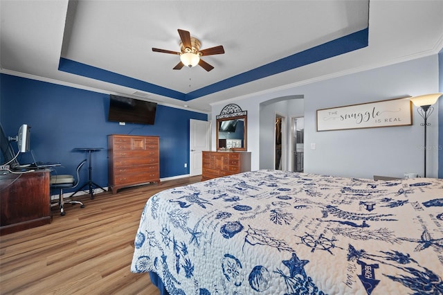 bedroom featuring a raised ceiling, crown molding, and wood finished floors