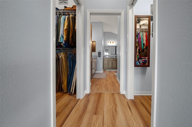 corridor with baseboards and light wood-style flooring