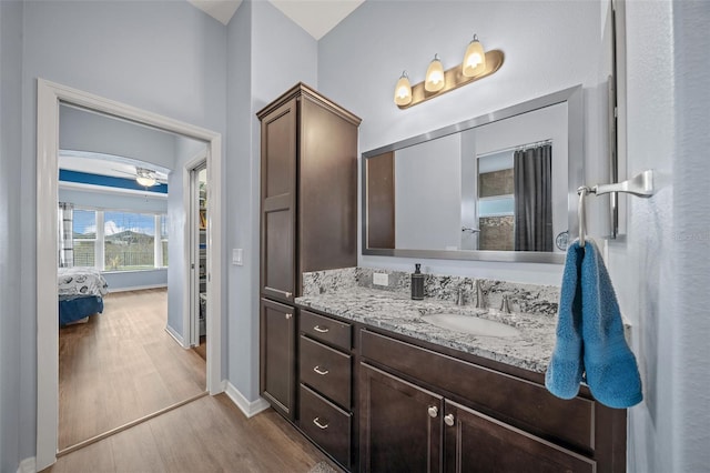 bathroom featuring ensuite bathroom, wood finished floors, baseboards, ceiling fan, and vanity