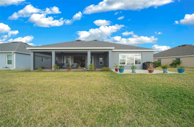 back of house featuring a yard, a patio area, a sunroom, and stucco siding