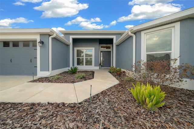 property entrance featuring stucco siding, driveway, and an attached garage