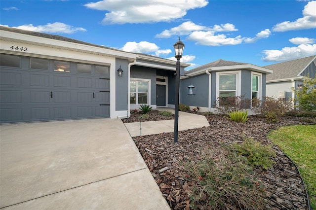 ranch-style home with stucco siding, a garage, and concrete driveway