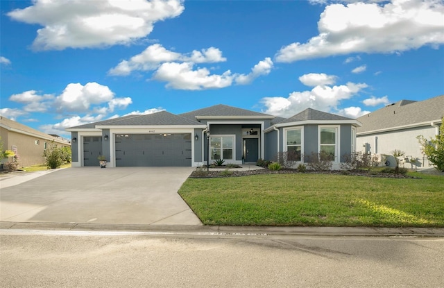 prairie-style house featuring stucco siding, an attached garage, concrete driveway, and a front lawn