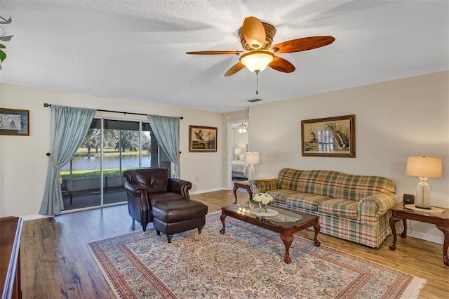 living room featuring hardwood / wood-style floors, a textured ceiling, and ceiling fan