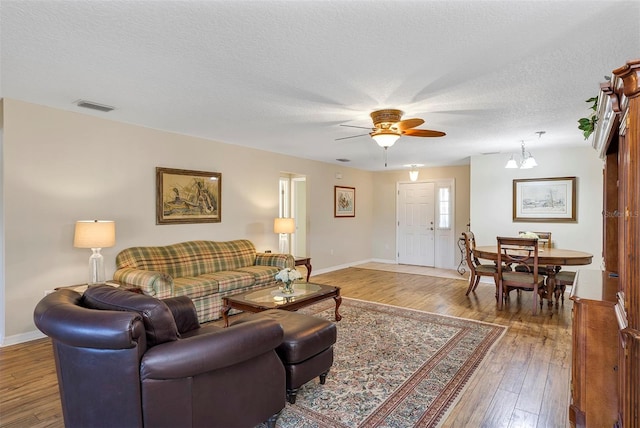 living room featuring ceiling fan, hardwood / wood-style flooring, and a textured ceiling