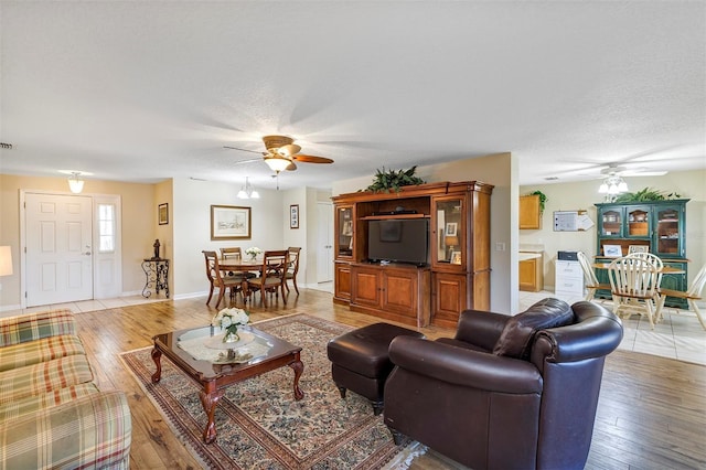 living room with hardwood / wood-style flooring, ceiling fan, and a textured ceiling