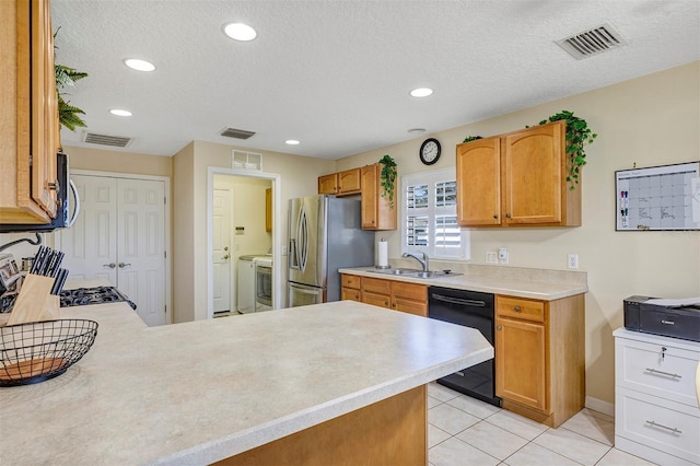 kitchen featuring sink, light tile patterned floors, stainless steel appliances, and a textured ceiling