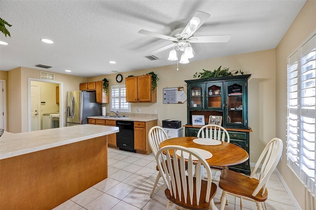 kitchen featuring sink, stainless steel fridge, dishwasher, a healthy amount of sunlight, and light tile patterned flooring