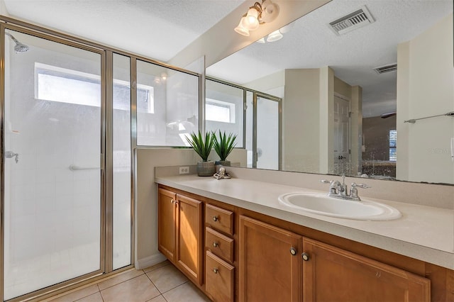 bathroom featuring tile patterned flooring, vanity, a textured ceiling, and a healthy amount of sunlight