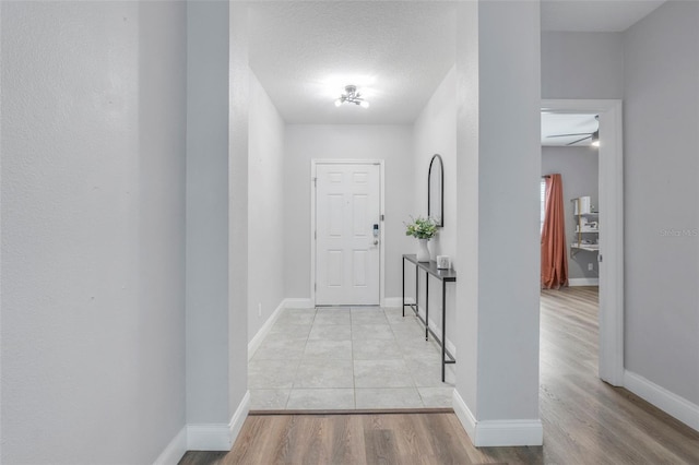 hall with a textured ceiling and light hardwood / wood-style floors