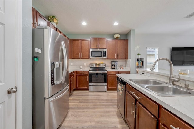 kitchen featuring stainless steel appliances, decorative backsplash, light hardwood / wood-style flooring, and sink