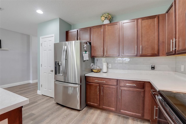 kitchen with backsplash, appliances with stainless steel finishes, a textured ceiling, and light wood-type flooring